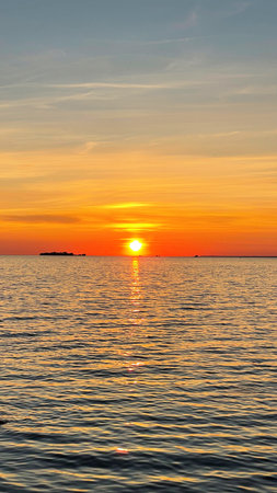 Beautiful sunset over the sea. The sun sets on the water. The sky is painted with bright colors. Sunny path on the water. Summer evening. Sunset beach. Vertical photographyの写真素材