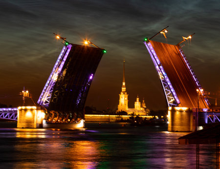 Neva river and raised Palace Bridge at white nights in St.Petersburg, Russia. View of Peter and Paul Cathedral through the bridge. Illumination of the night cityの写真素材
