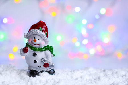 Snowman in the snow with bokeh blurred light.