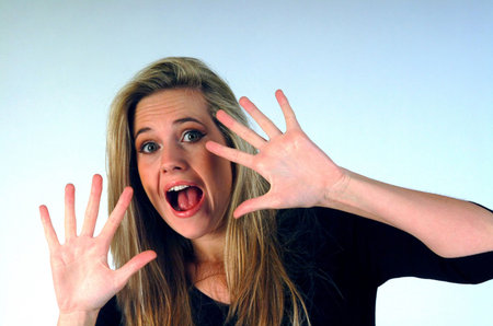 Woman with hands near face looking scared.の写真素材