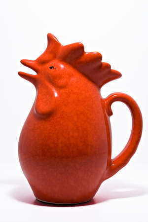 A shot of an old fashion red cockerel gravy jug, on a white background.の写真素材