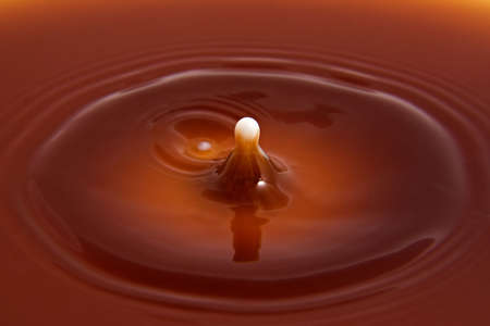 Extreme close up shot of a drop of milk landing in a cup of hot chocolate.の写真素材
