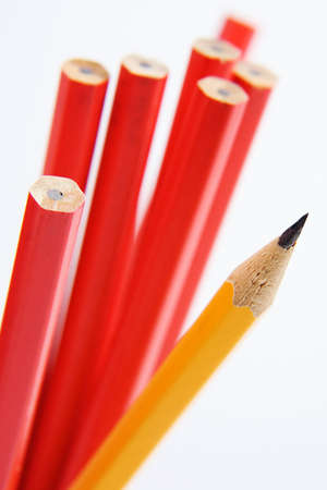 Close up shot of a sharp yellow pencil amongst unsharpened red pencils. Narrow depth of field.の写真素材
