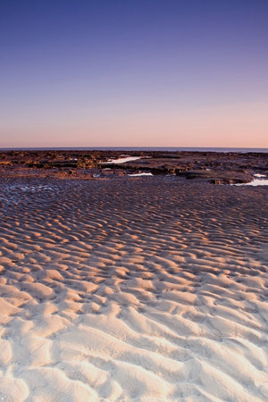 Ripples in the sand during low tide at sunrise.