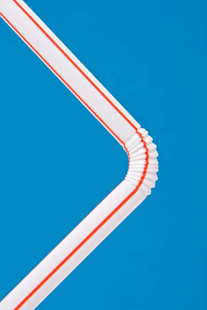 Close up shot of a bent plastic straw on a blue background.の写真素材