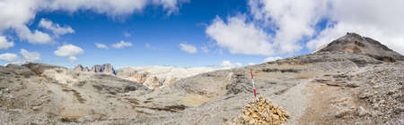 Stone pyramid nearby a trail on the Sass Pordoi to the Piz Boe, a Mountain peak in the Dolomites and a view to the Sassolungo on the leftside.の写真素材