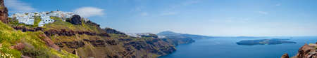 Daisy flowers at the village of Imerovigli, showing a the wide coastline with the Nea Kameni island in the ocean.