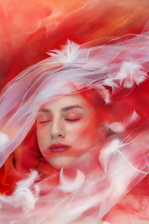 A conceptual depiction is showing the inner silence and softness of passionate dreams, through the white and red color veils and an evening sky in the background.の写真素材