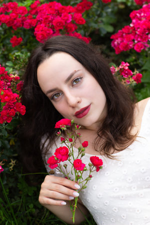 A romantically attracted woman in a white dress is gently holding roses.の写真素材