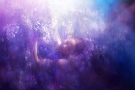 Young woman under a Kolkwitzia bush at Springtime, with a blurred falling blossoms effect.の写真素材