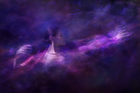 A female with a cross necklace, covered in a transparent veil over her shoulders, is elegantly dancing through sparks of light.の写真素材