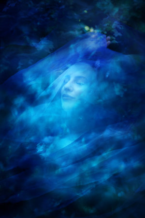 A woman, at Hortensia flowers in summer, shows a sublime, majestic expression, while being covered in a blue veil.の写真素材