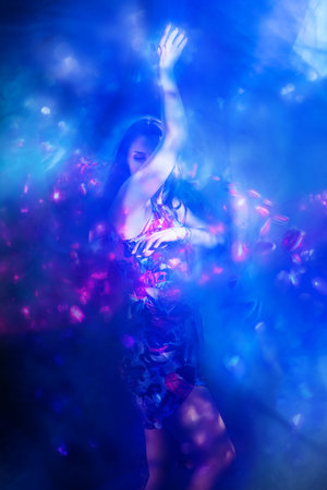 A joyful woman is dancing with her arms raised, captured in a dynamic and vibrant pose.