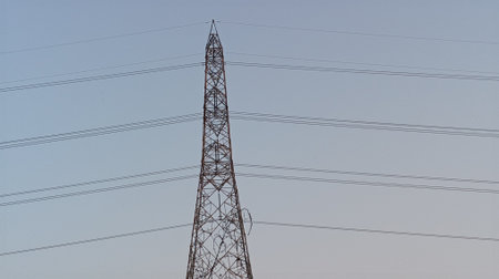 High voltage power lines and pylons against clear blue sky.
