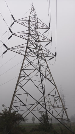 Electricity pylons and power lines in a foggy morning