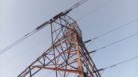 High voltage power lines and pylons against a blue sky.