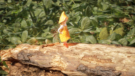 A cute little elf is resting and walking in the summer sunny green forest. Fairy elven magic...