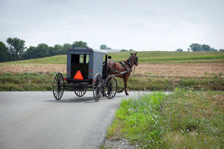 An Old Order Amish buggy turns a corner in Lancaster County Pennsylvaniaの写真素材
