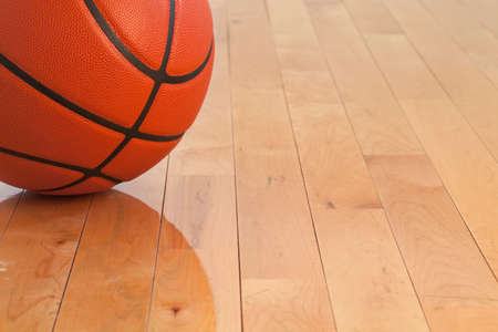 Low angle view of a basketball on a wooden gymnasium floorの写真素材