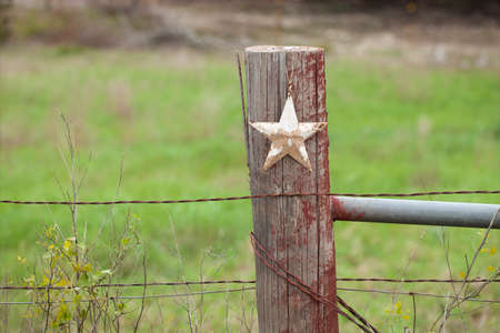 A selective focus view of a grungy white star on a wooden fence post in Texasの写真素材