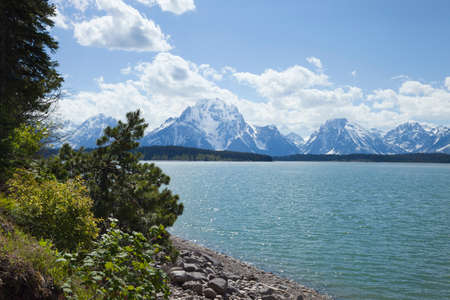 Jackson Lake below the Grand Teton mountain range on a sunny afternoonの写真素材