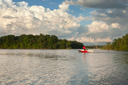 Speedboat heads out onto a Minnesota lake in evening sunlight below dramatic cloudsの写真素材