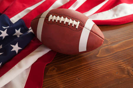 College style football with an American flag on a dark pine wood backgroundの写真素材