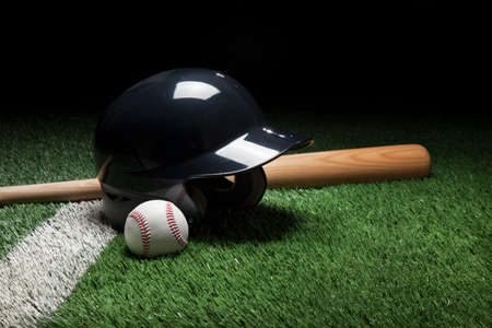 Baseball batting helmet bat and ball on field with stripe and dark backgroundの写真素材