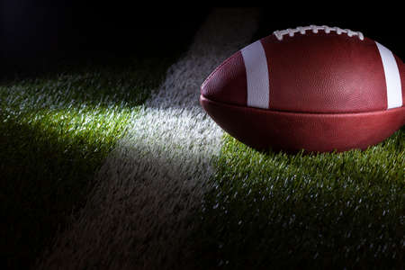 Low angle selective focus view of a football on a yard line with dramatic lightingの写真素材