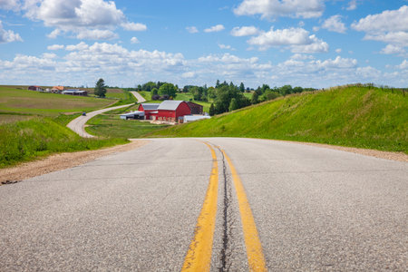 Farm with a red barn on a curving road in the Iowa countryside on a bright spring dayの写真素材