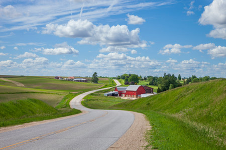 Farm with a red barn on a curving road in the Iowa countryside on a beautiful spring dayの写真素材