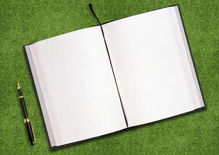 blank opened book outdoors on the green grassland and penの写真素材