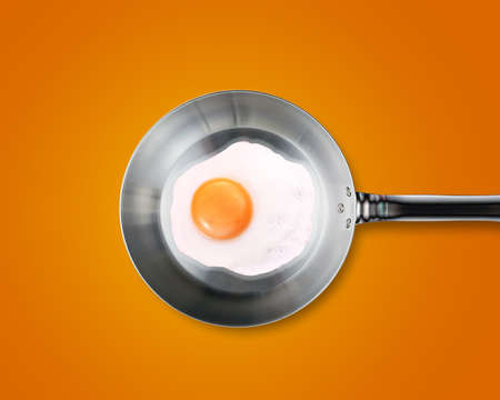 Fried egg in a frying pan on orange background