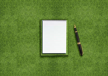 blank opened notebook outdoors on the green grassland and penの写真素材