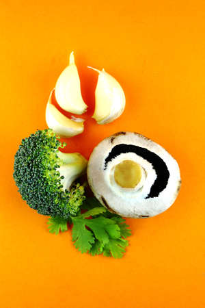 button mushrooms with garlic, parsley and broccoli on orange background.の写真素材