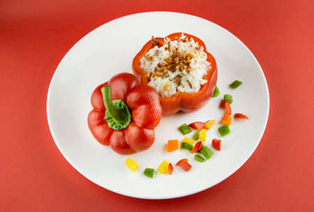 Stuffed red pepper in a dish on red background .の写真素材