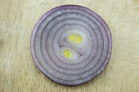 Red sliced onion on wooden kitchen board.
