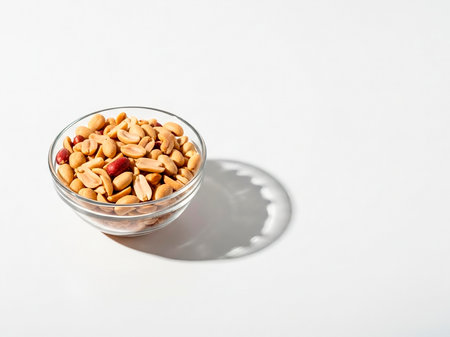 Peanuts in a glass bowl on a white background with a shadowの素材