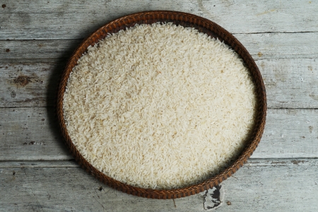 thai jasmine rice in threshing basket on wooden tableの写真素材