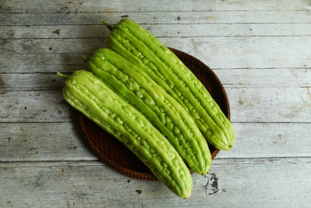 Bitter melons in the threshing basket on wooden tableの写真素材