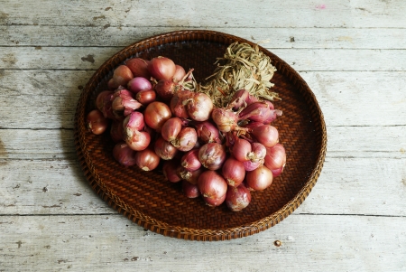 Shallot - red onion in the threshing basket on wooden tableの写真素材