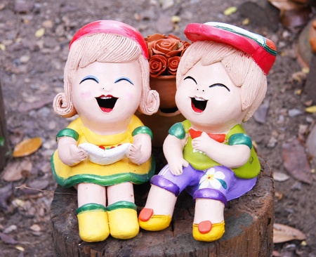 two pretty girls baked clay dolls ornamental in the gardenの写真素材