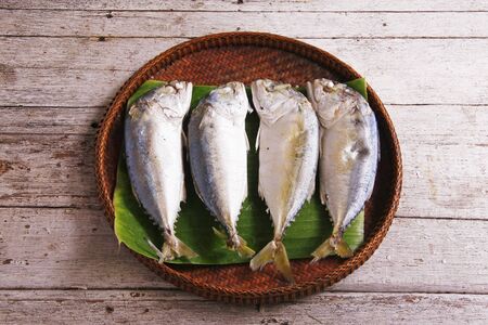 Mackerel fishes in bamboo basket on wooden table