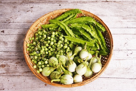 eggplants, turkey berry, winged bean in the threshing basket on wooden tableの写真素材