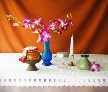 still life with earthen bowl,vase,orchid,silver bowl,glass tray with pedestal,brass tray with pedestal,candle, Porcelain lamp and jasmine garland  の写真素材