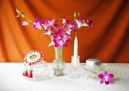 still life with glass bowl,vase,orchid,si lver bowl,glass tray with pedestal,candle and jasmine garlands の写真素材