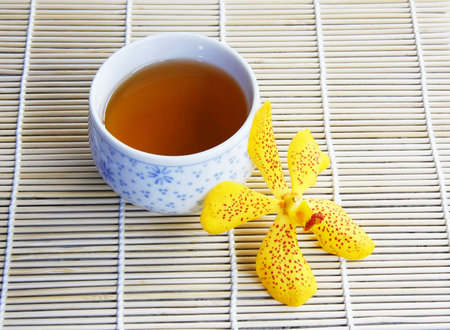 still life with cup of tea and orchid flower on wooden table の写真素材