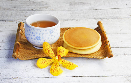 Dorayaki Japanese Traditional Pancake Dessert with cup of tea in bamboo tray on wooden table の写真素材