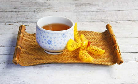 still life with cup of tea in bamboo tray and orchid flower on wooden table の写真素材