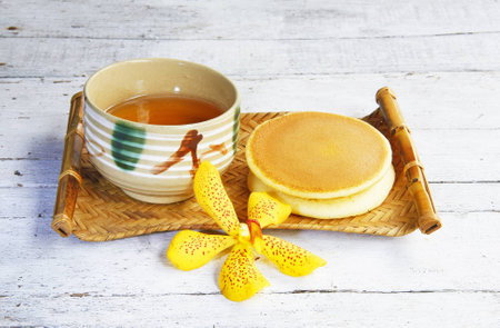 Dorayaki Japanese Traditional Pancake Dessert with cup of tea in bamboo tray on wooden table の写真素材
